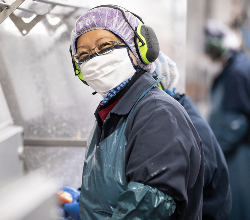 Happy employee works in processing plant wearing protective equipment